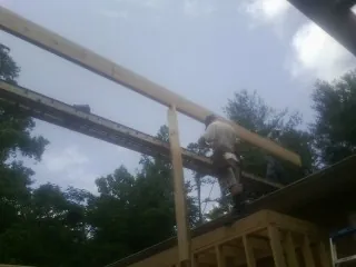 Carpenter setting a ridge beam over a new addition frame — Ice Dam Removal by Roofing Brothers in Tappahannock