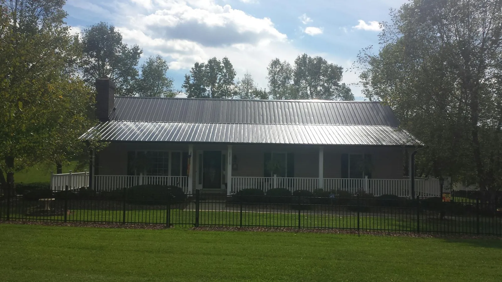 Gray metal roof on a brick ranch with a full width front porch — Gutter Guard Installation work by our crew in Tappahannock