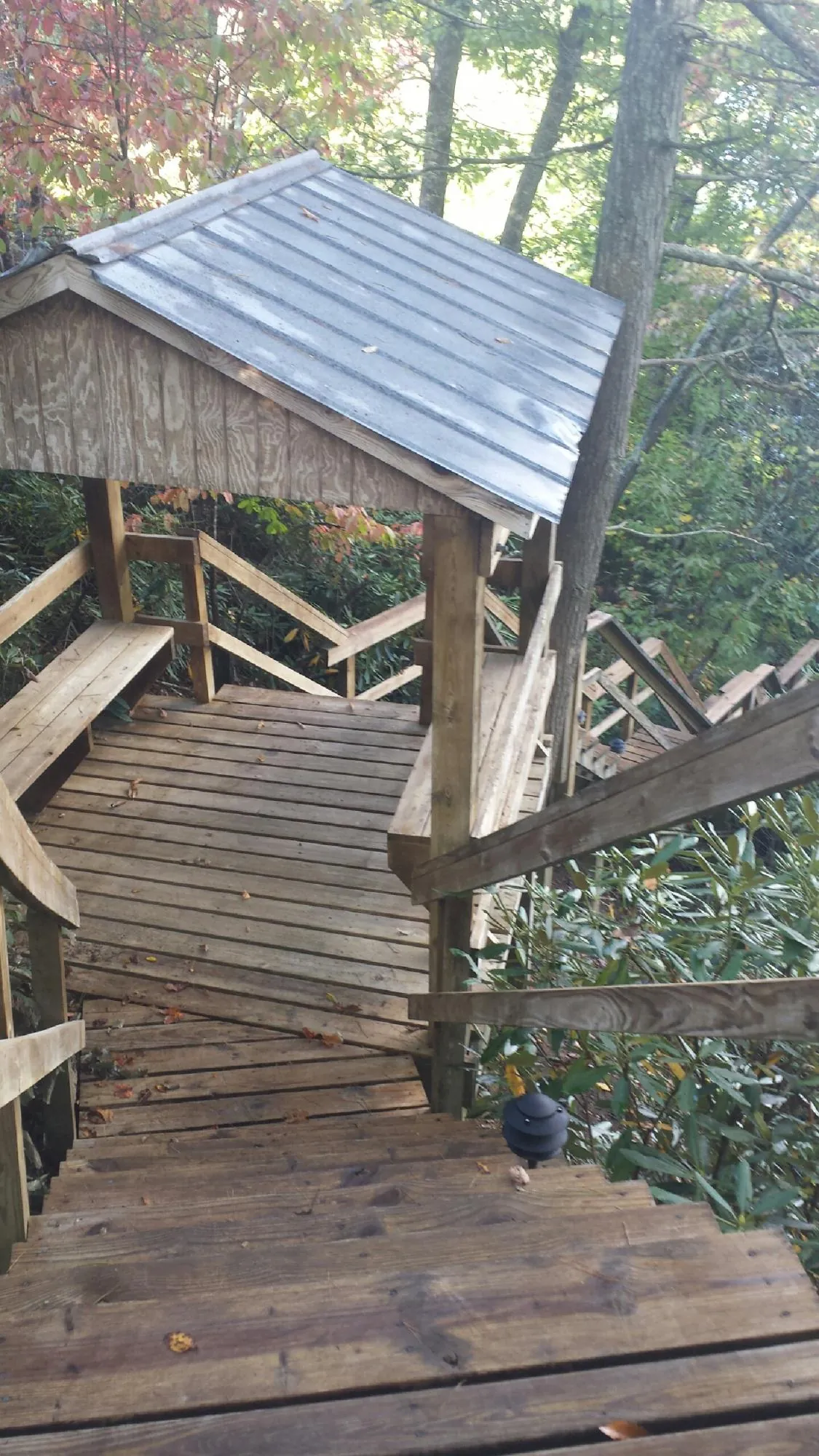 Metal roofed shelter over wooden steps on a wooded walkway — Skylight Repair & Installation work by our crew in Tappahannock