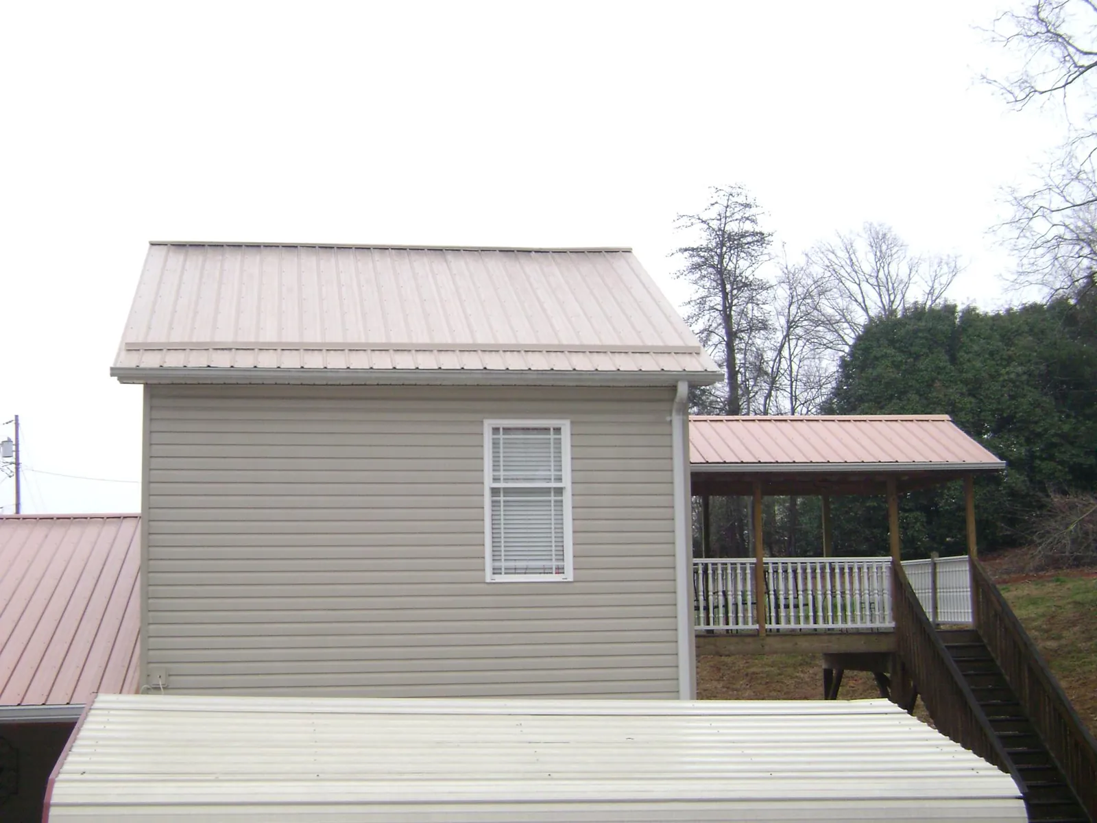Tan metal roofs on a two story addition and attached porch, from a Roof Replacement job in Tappahannock