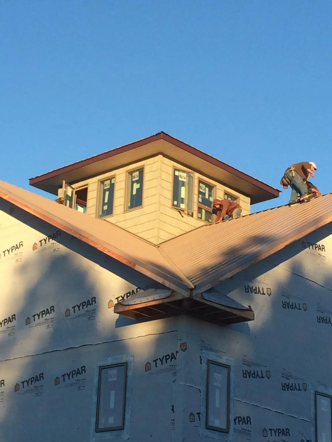 Roofers working around a rooftop cupola on a new metal roof at sunset — Roof Waterproofing in Tappahannock by Roofing Brothers